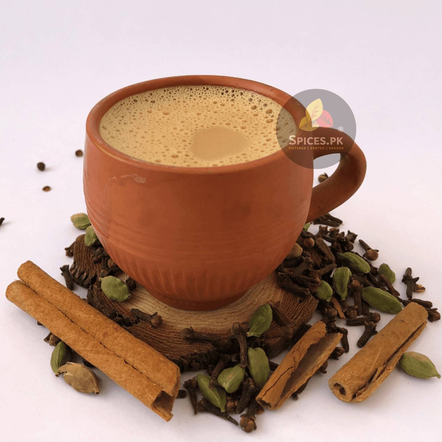 Traditional Pakistani Chai Masala blend by Spices.pk. Organic Matka Karak Chai with cinnamon, cardamom, and cloves,Terracotta mug with a beverage surrounded by spices on a white background