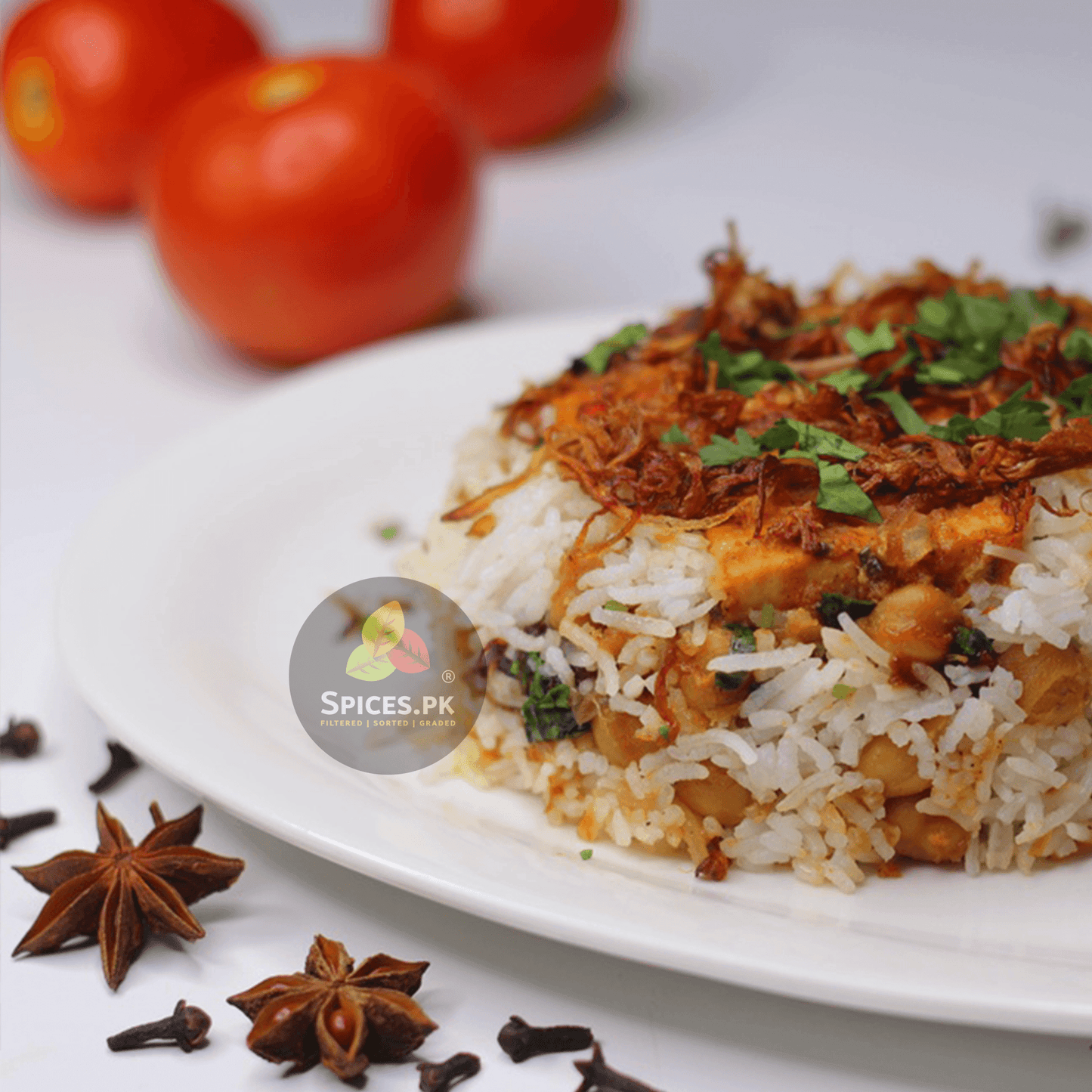Organic Chana Pulao and Biryani Masala by Spices.pk. Premium, preservative-free spice blend for authentic Pakistani chickpea rice.Plated dish of rice with a topping, garnished with herbs, on a white plate with tomatoes and spices in the background.