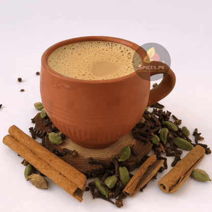 Traditional Pakistani Chai Masala blend by Spices.pk. Organic Matka Karak Chai with cinnamon, cardamom, and cloves,Terracotta mug with a beverage surrounded by spices on a white background