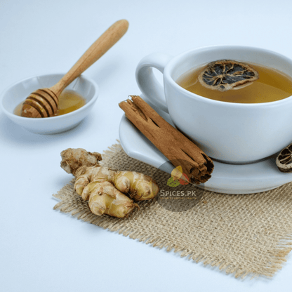 Cinnamon honey ginger tea cup served with raw ginger root, a cinnamon stick, and pure honey by Spices.pk Pakistan.