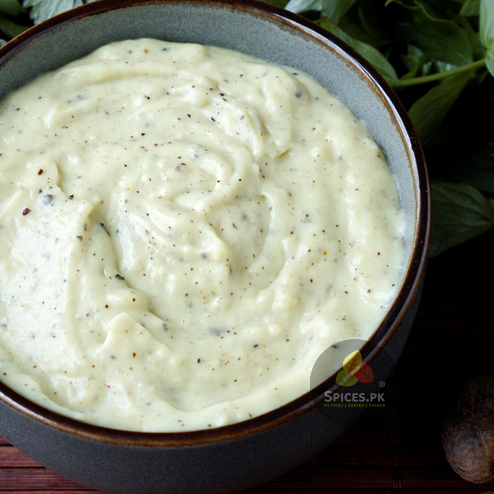 Creamy white bechamel sauce seasoned with freshly ground nutmeg powder in a bowl by Spices.pk