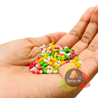 A handful of colorful sugar coated fennel seeds (Meethi Saunf) showing the premium size and bright colors of Spices.pk sweet pack.