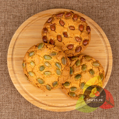 Healthy home-baked cookies topped with unroasted pumpkin seeds and nuts served on a round wooden board.