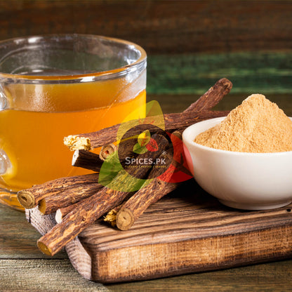 Dried licorice root sticks next to a bowl of mulethi powder and a clear glass cup of herbal tea for cough relief.