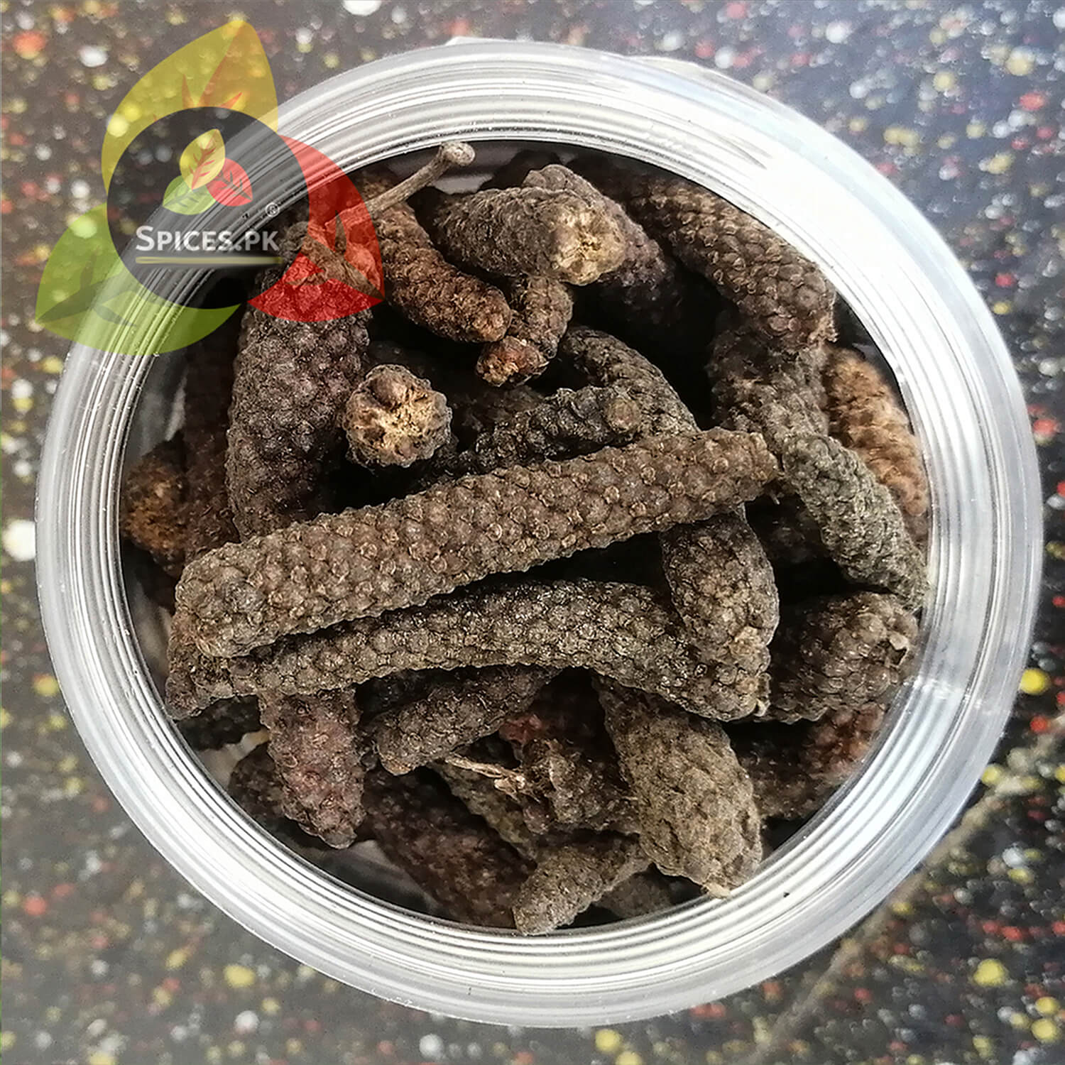 Close-up top view of textured whole Pipli spice pods inside a transparent jar, showcasing filtered premium grade quality by Spices.pk.