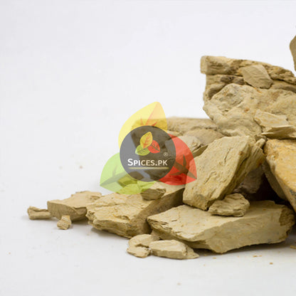 Raw, pure organic Multani Mitti stones piled on a clean white background by Spices.pk, ideal for an all-natural skincare routine.