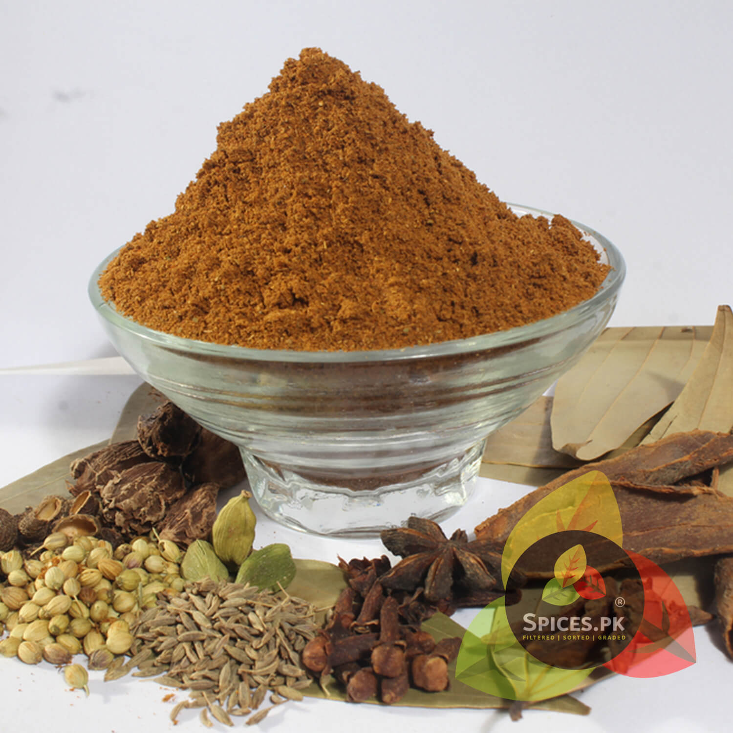 Garam Masala Powder served in a glass bowl surrounded by its raw whole spice ingredients like star anise and coriander. Spices.pk ensures premium quality, hand-sorted, and foil-sealed freshness.