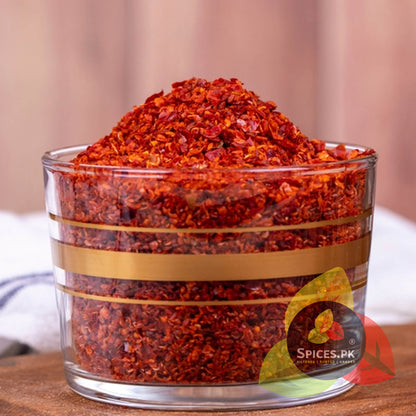 Rich, vibrant Red Chilli Flakes piled high in a glass bowl, showcasing the natural texture and color of Spices.pk seasonings.
