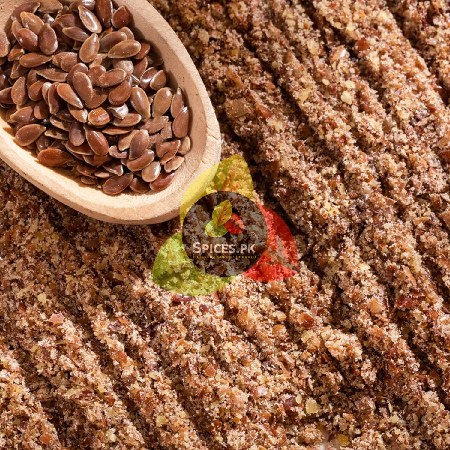 Macro view of whole alsi seeds in a wooden spoon placed over finely ground organic flaxseed powder texture.Wooden scoop filled with flaxseeds on a bed of ground flaxseed with Spices PK logo.