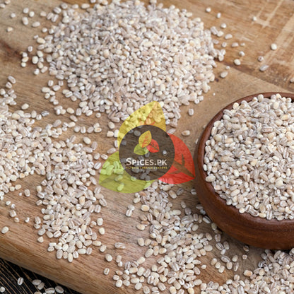 Premium raw whole barley seeds scattered on a wooden cutting board showing the natural source of jau ka daliya.
